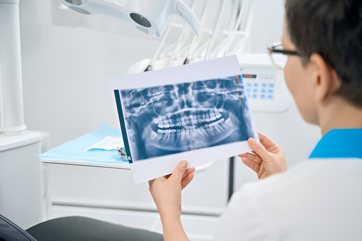 periodontologė tiria paciento žandikaulio rentgeno vaizdą